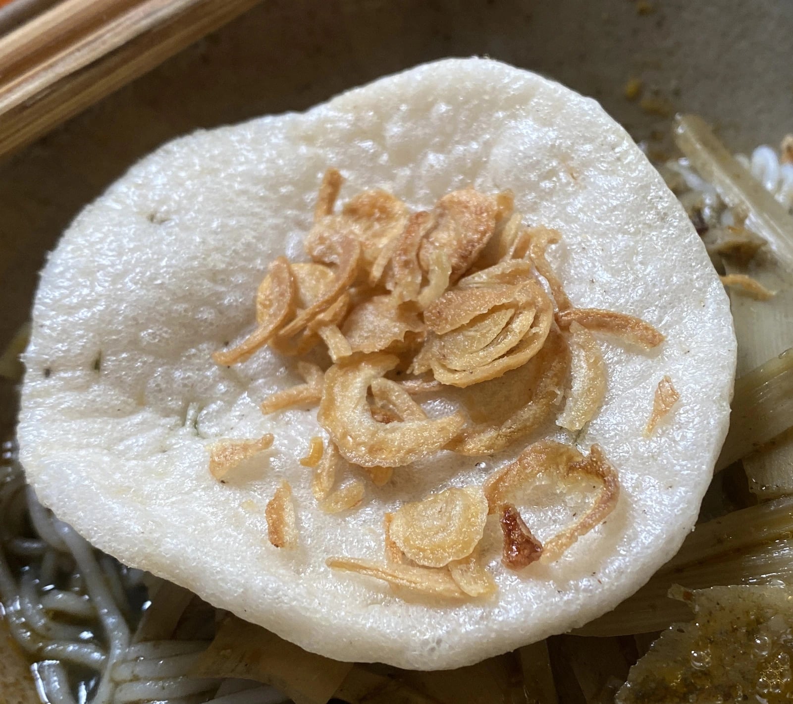 Stinky crab noodles are served with veggies, rice crackers and fried sliced shallots.