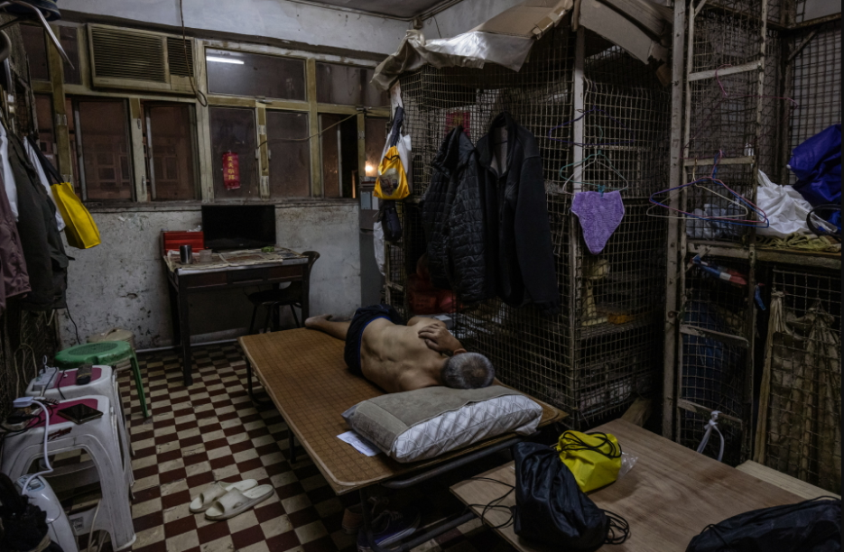 A man lies in a cage home unit, a type of housing that has become increasingly rare in Hong Kong due to its harsh conditions, now largely replaced by “coffin” homes, in Hong Kong, China, July 10, 2024. Photo: Reuters