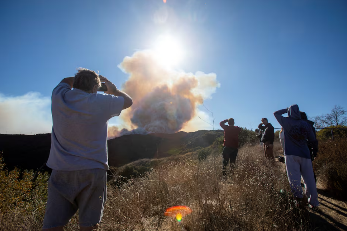 People watch smoke rising from the Palisades Fire, one of simultaneous blazes that have ripped across Los Angeles County, in the Tarzana neighborhood of Los Angeles, California, U.S. January 11, 2025. Photo: Reuters