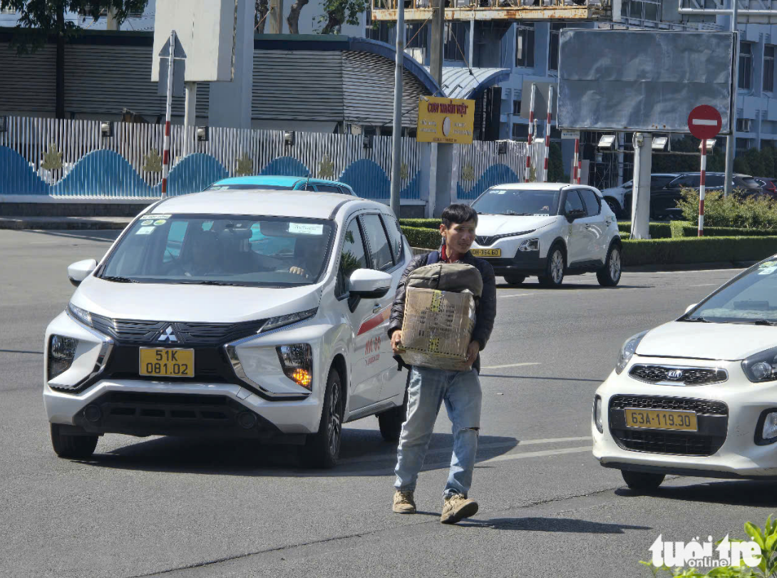 Failing to wait for a taxi, some passengers carry their luggage and head to Truong Son Street to easily hail a ride. Photo: Cong Trung / Tuoi Tre