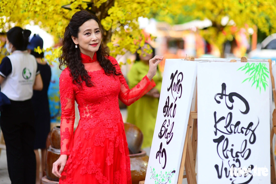 Artist Tuyet Thu poses for a photo next to calligraphic works at the 2025 Vietnamese Tet Festival at the Youth Culture House in Ho Chi Minh City, January 13, 2024.