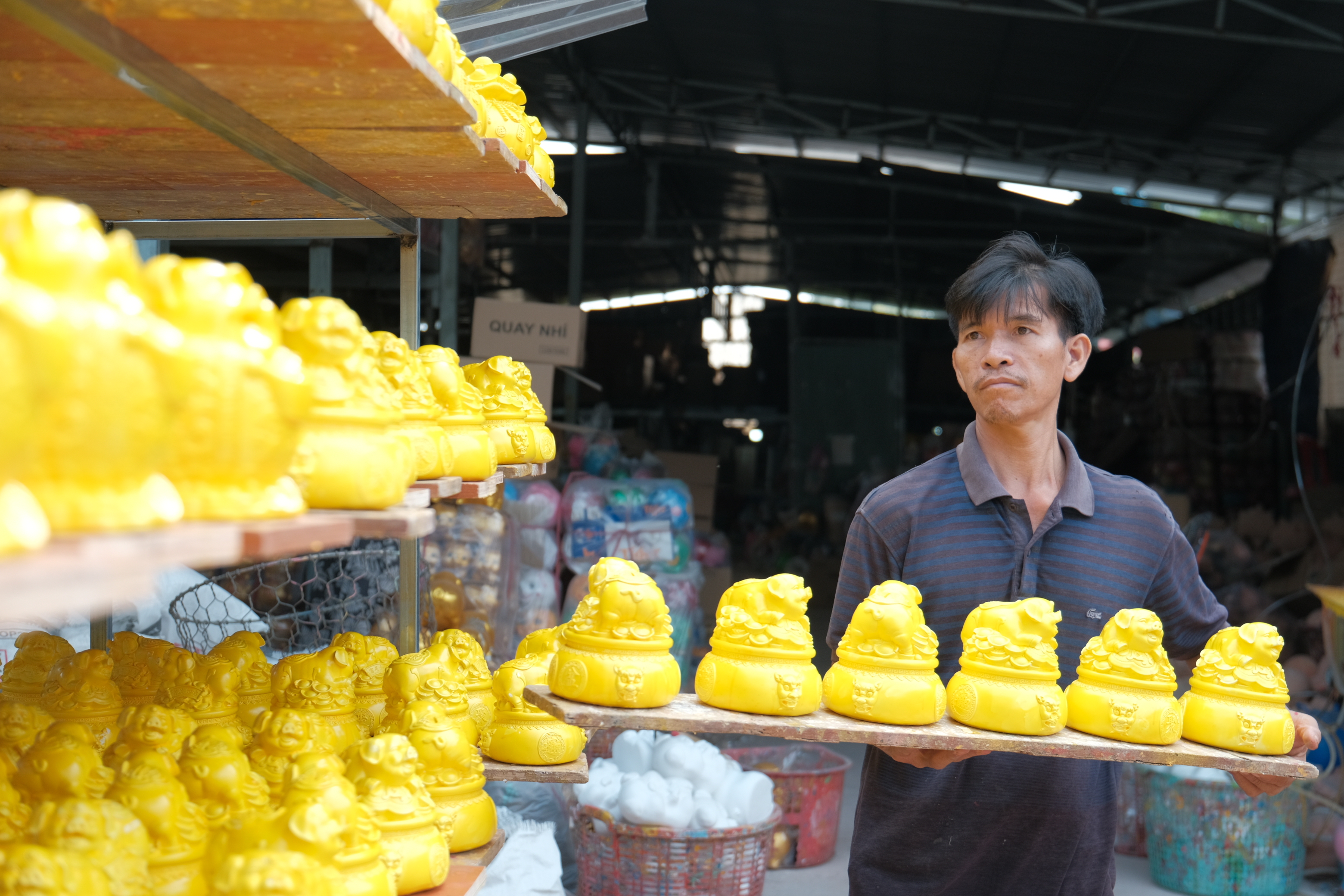 Nguyen Thanh Tam, owner of a workshop in Binh Duong Province, dries the painted piggy banks under the sun. Photo: Ngoc Phuong / Tuoi Tre News