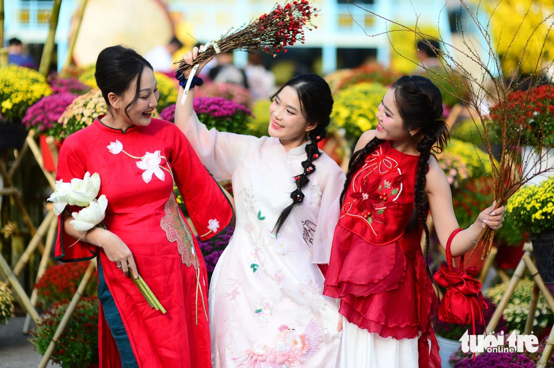 Young Vietnamese women donning ‘ao dai’ (Vietnamese traditional long gown) (L, C) and another in ‘ao yem,’ a traditional Vietnamese bodice, pose for a photo at the 2025 Vietnamese Tet Festival at the Youth Culture House in Ho Chi Minh City, January 13, 2024.