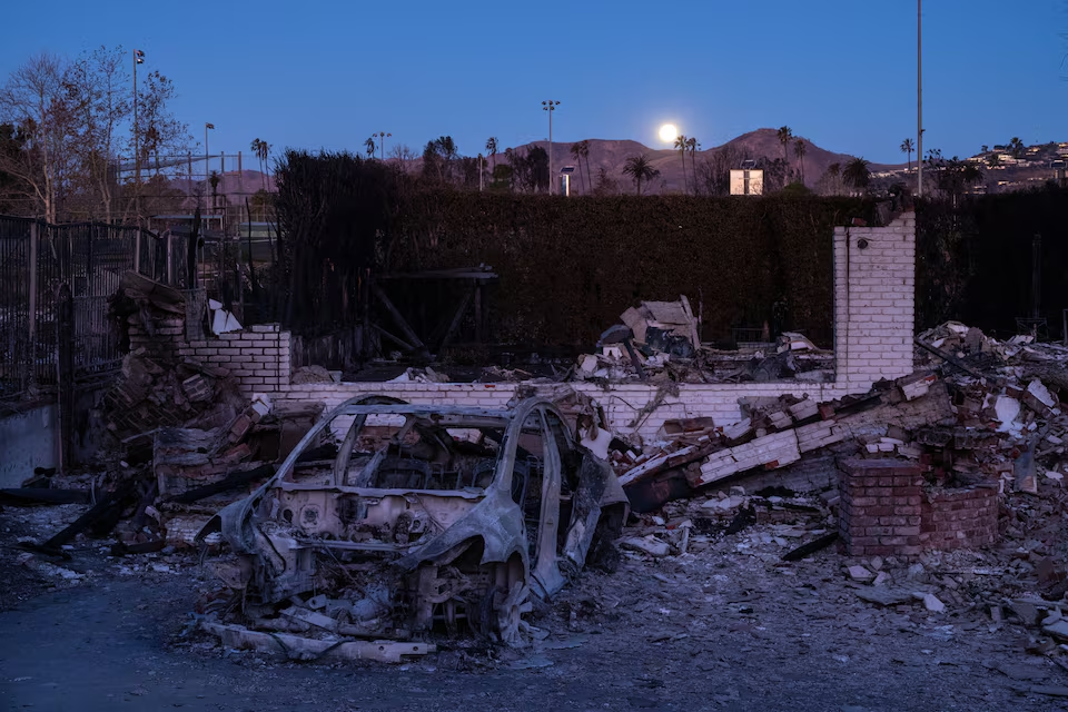 Remains of a property, destroyed by the Palisades Fire, are seen as the moon sets on the horizon at the Pacific Palisades neighborhood in Los Angeles, California, U.S. January 13, 2025. Photo: Reuters