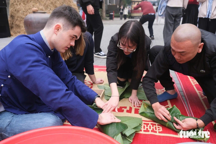 Louis Wald (L, 1st), a 20-year-old German student, practices wrapping banh chung during a Tet experience program at the Foreign Trade University in Hanoi, Vietnam, January 14, 2025. Photo: Nguyen Bao / Tuoi Tre