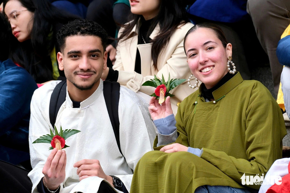 Two international students hold trau tem canh phuong (quids of betel with ‘Phoenix wings’) during a Tet experience program at the Foreign Trade University in Hanoi, Vietnam, January 14, 2025. Photo: Nguyen Bao / Tuoi Tre