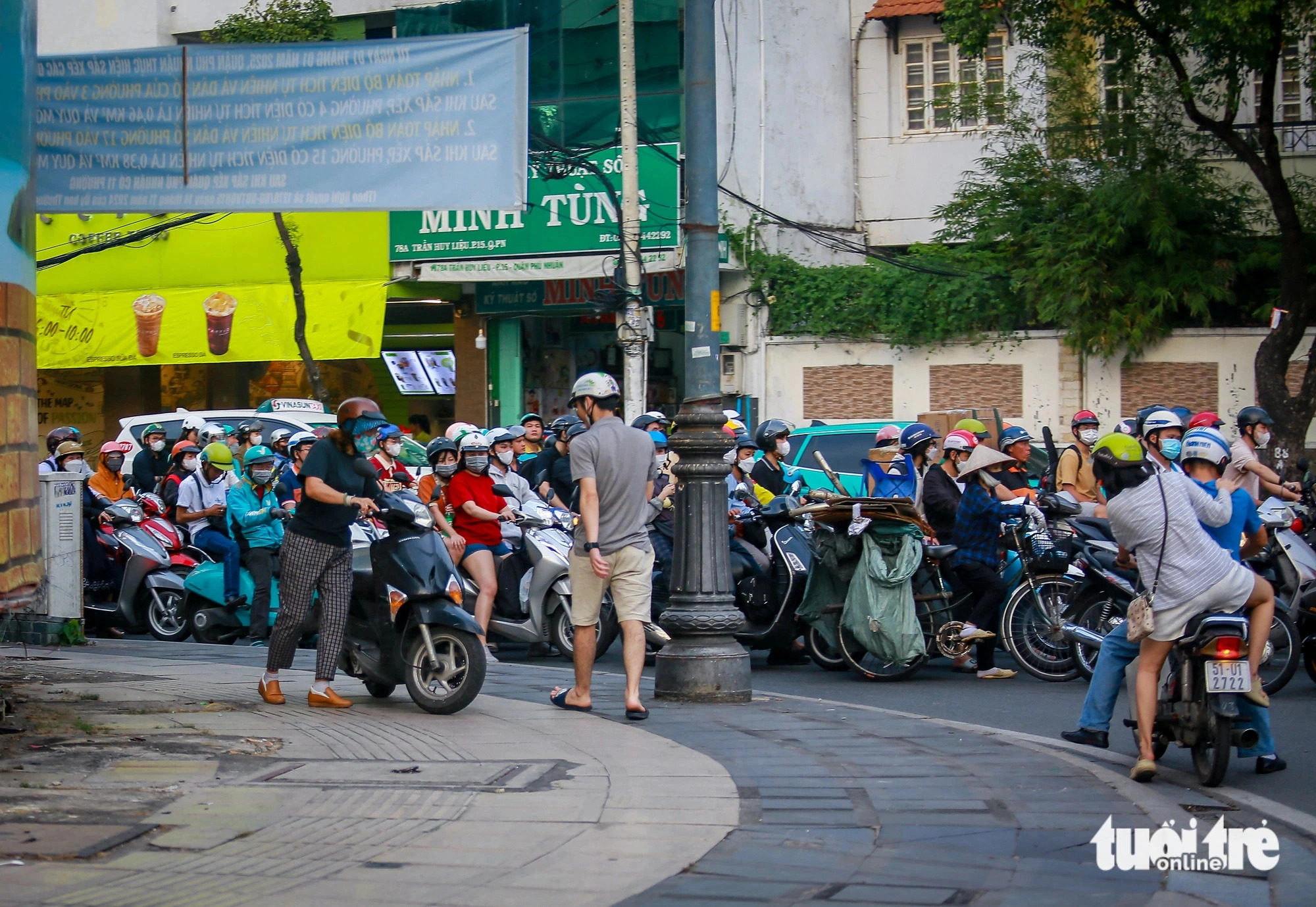 Riders push their motorcycles along sidewalks to escape traffic jams. Photo: Chau Tuan / Tuoi Tre