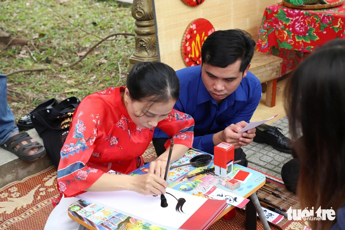 Vilasan Sommixay (R) from Laos waits for a calligrapher to complete a calligraphic work.