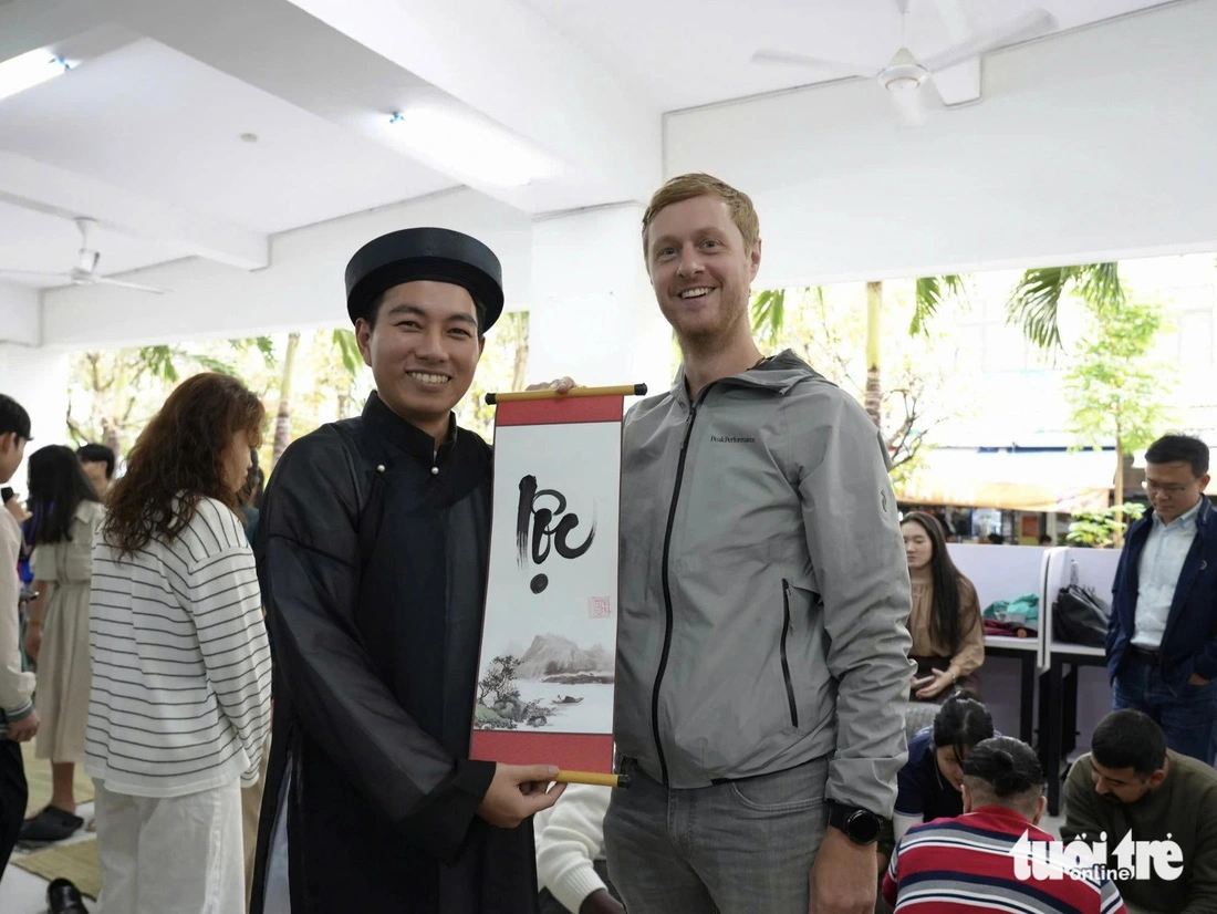 Nathan, a student from Austria, is interested in a piece of calligraphy presented by a Vietnamese calligrapher.