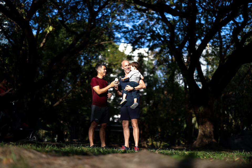 A gay couple, Jacob Holder, 45, holds up his son, Elijah Bprin Holder Koonpaew, as Surapong 'Keng' Koonpaew stands as they spend time together at a park in Bangkok, Thailand, January 11, 2025. Photo: Reuters