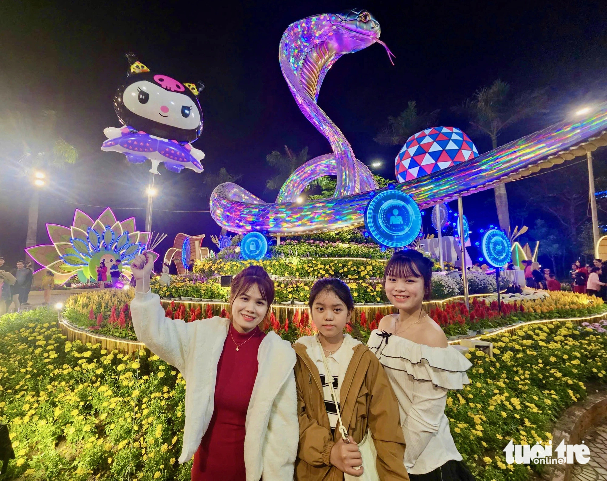 Visitors pose for a group photo next to a giant snake mascot on the Tet flower street. Photo: Minh Chien / Tuoi Tre