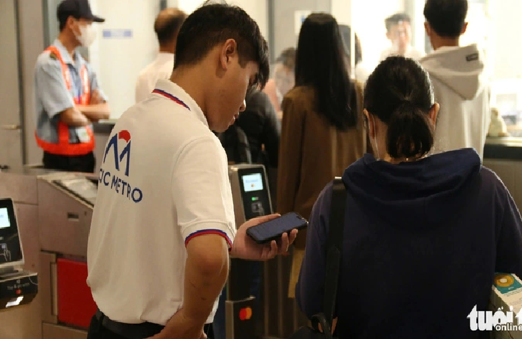 An employee of Ho Chi Minh City Urban Railway No. 1 Co. Ltd. instructs a local passenger to make cashless payments to avoid queueing up. Photo: Bui Nhi / Tuoi Tre