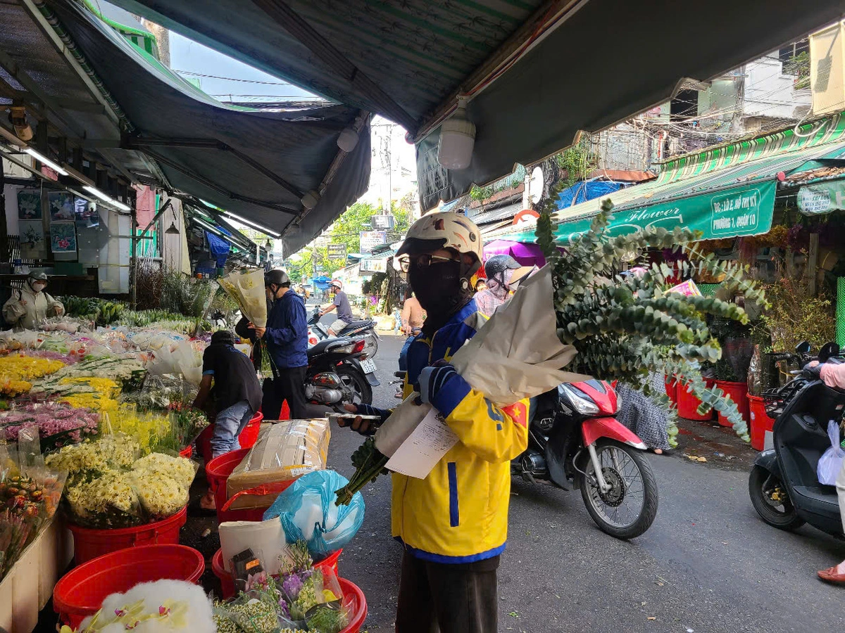 A delivery man picks up flowers from a trader in Ho Chi Minh City. Photo: Nhat Xuan / Tuoi Tre