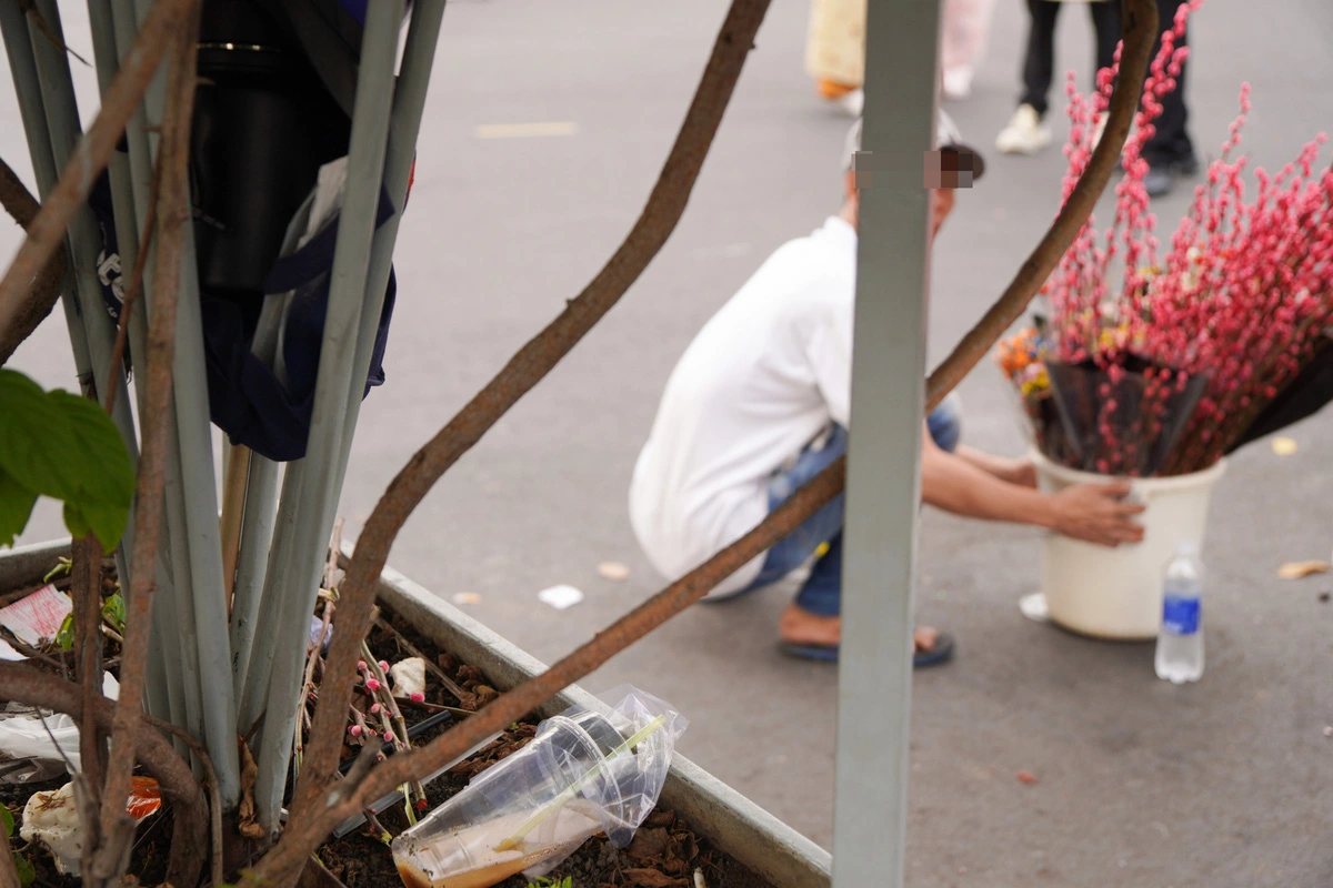 Flower vendors discard withered branches and flower petals in front of Ben Thanh Market in Ho Chi Minh City. Photo: An Vi / Tuoi Tre