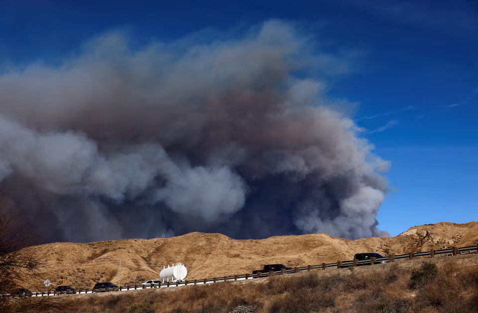 [7/13]A cloud of smoke from the Hughes Fire rises as firefighters battle it near Castaic Lake, north of Santa Clarita, as seen from a highway nearby, California, U.S. January 22, 2025. Photo: Reuters