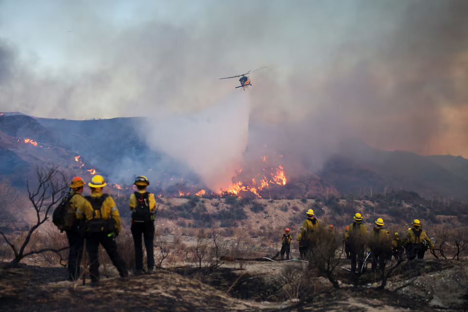 [2/13]A helicopter drops water as the Hughes Fire burns in Castaic Lake, California, U.S. January 22, 2025. Photo: Reuters