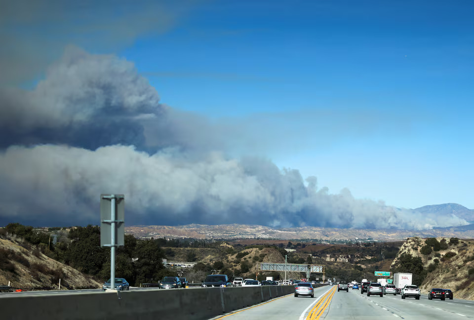 [9/13]Vehicles drive on a highway and a cloud of smoke rises on the background as firefighters and aircraft battle the Hughes Fire near Castaic Lake, north of Santa Clarita, California, U.S. January 22, 2025. Photo: Reuters