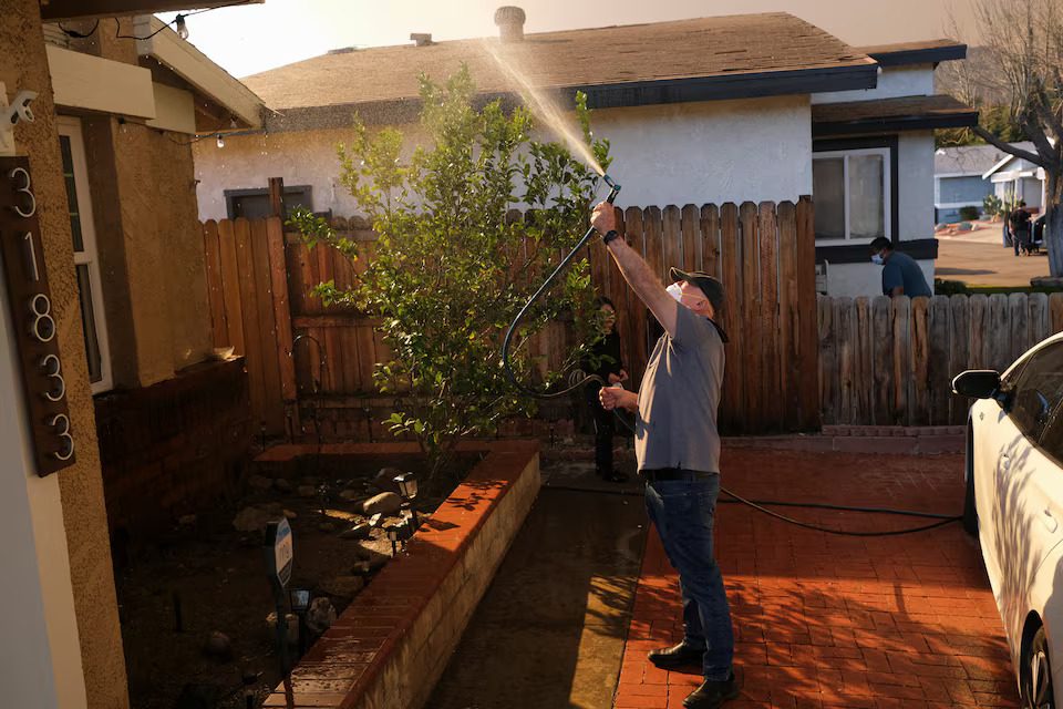 [6/13]Thomas Carbajal sprays down his home with water as the Hughes Fire burns, in Castaic, California, U.S., January 22, 2025. Photo: Reuters