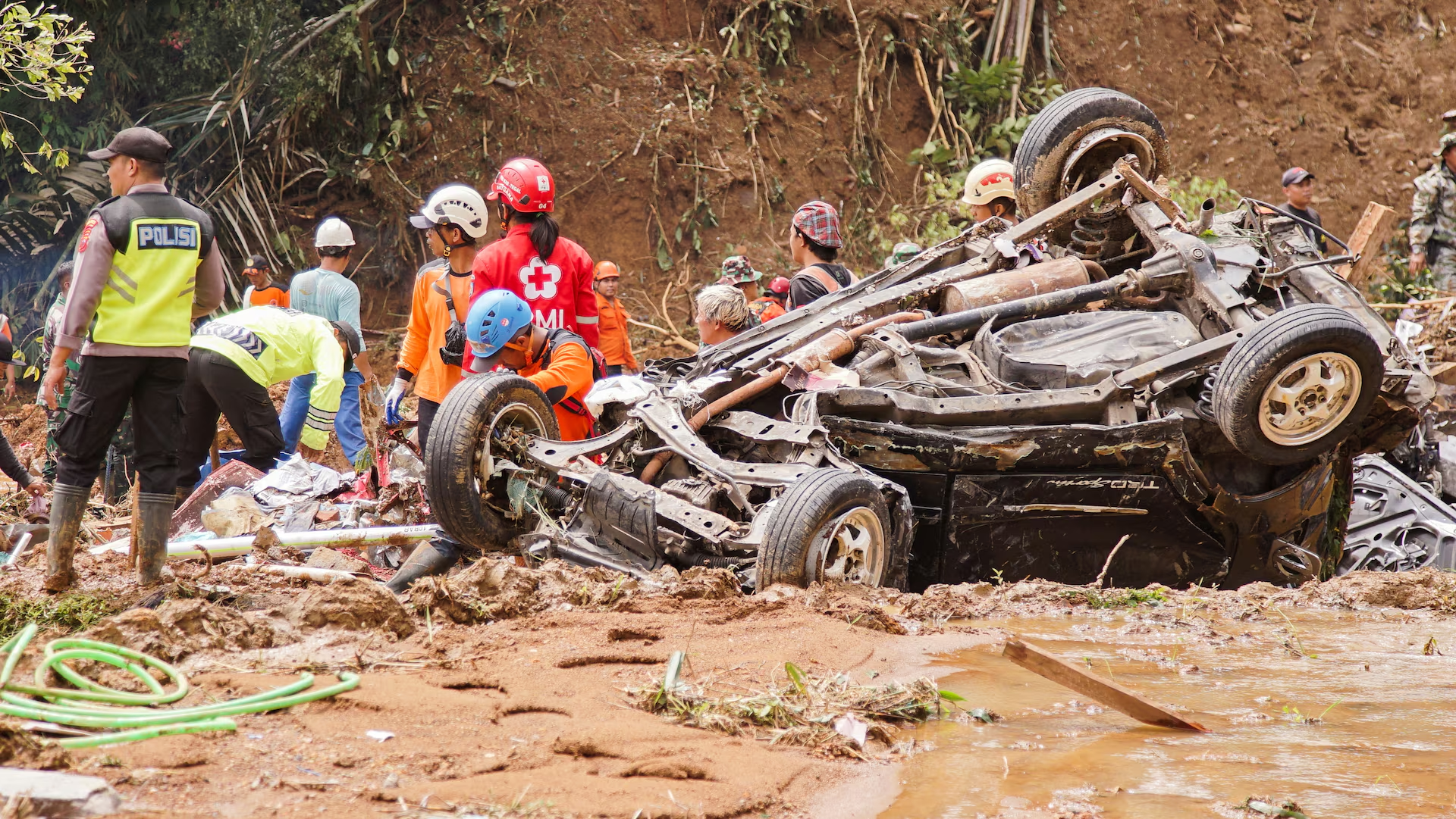 Indonesian rescuers and police officers stand near a damaged car at the site of a landslide caused by heavy rains in Pekalongan, Central Java province, Indonesia January 22, 2025. Photo: Reuters