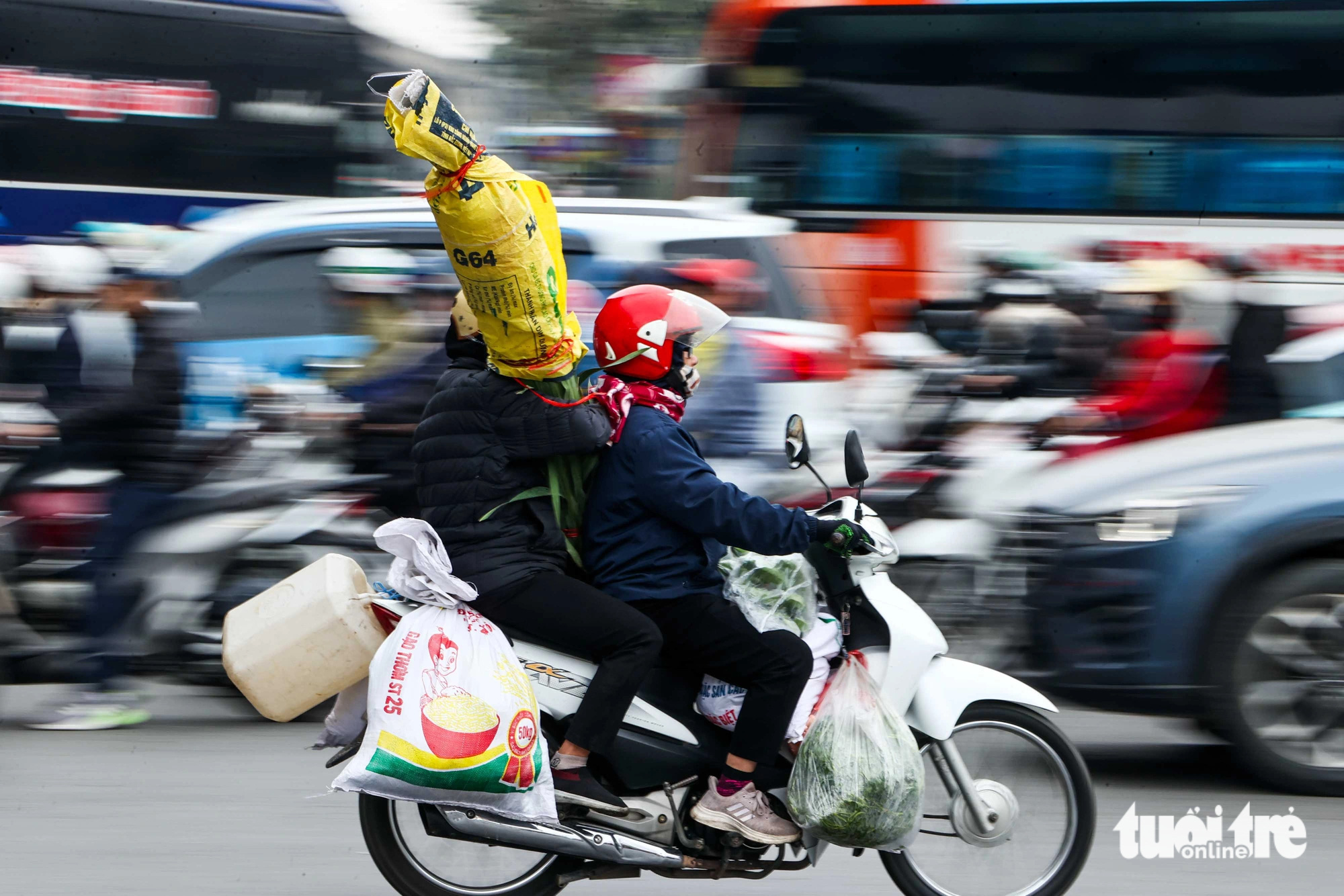 People carry flowers and vegetables on motorbike amid heavy traffic in Hanoi, January 25, 2025. Photo: Nguyen Khanh / Tuoi Tre