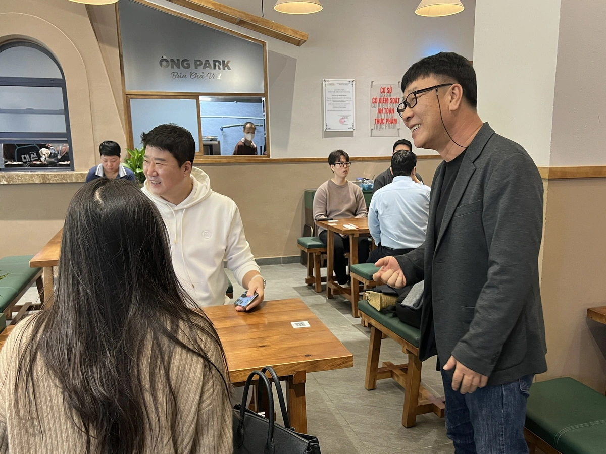 Park Chung Gun (R) warmly welcomes customers and introduces ‘bun cha’ to them. Photo: Hoang Tung / Tuoi Tre