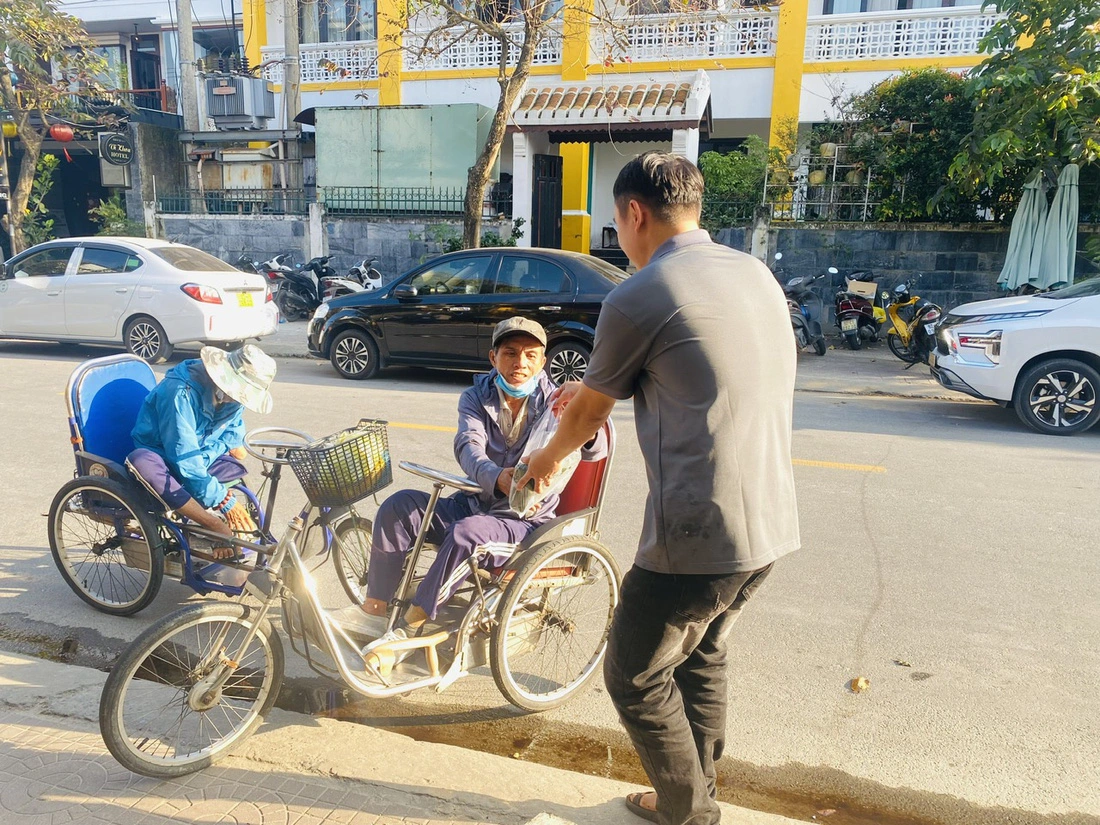 A staff member of Boi Com Hoi An Restaurant & Café in Hoi An City, Quang Nam Province, central Vietnam offers 'banh chung' and 'banh tet' to underprivileged people. Photo: Nhan Quy