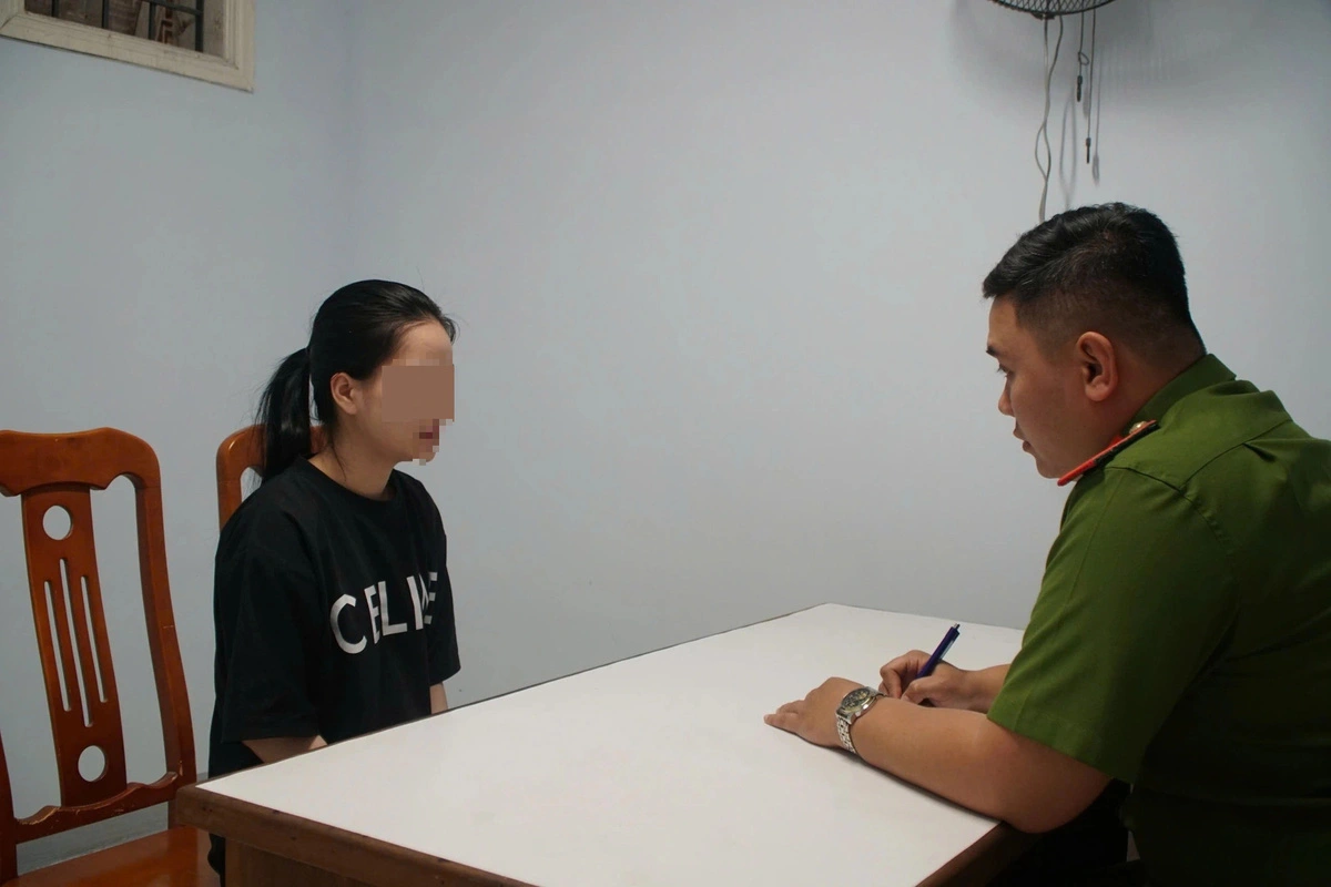 A Vietnamese police officer in Da Nang City, central Vietnam is seen questioning a woman who is one of the five Vietnamese suspects involved in a Chinese-led international fraud ring. Photo: H.B.