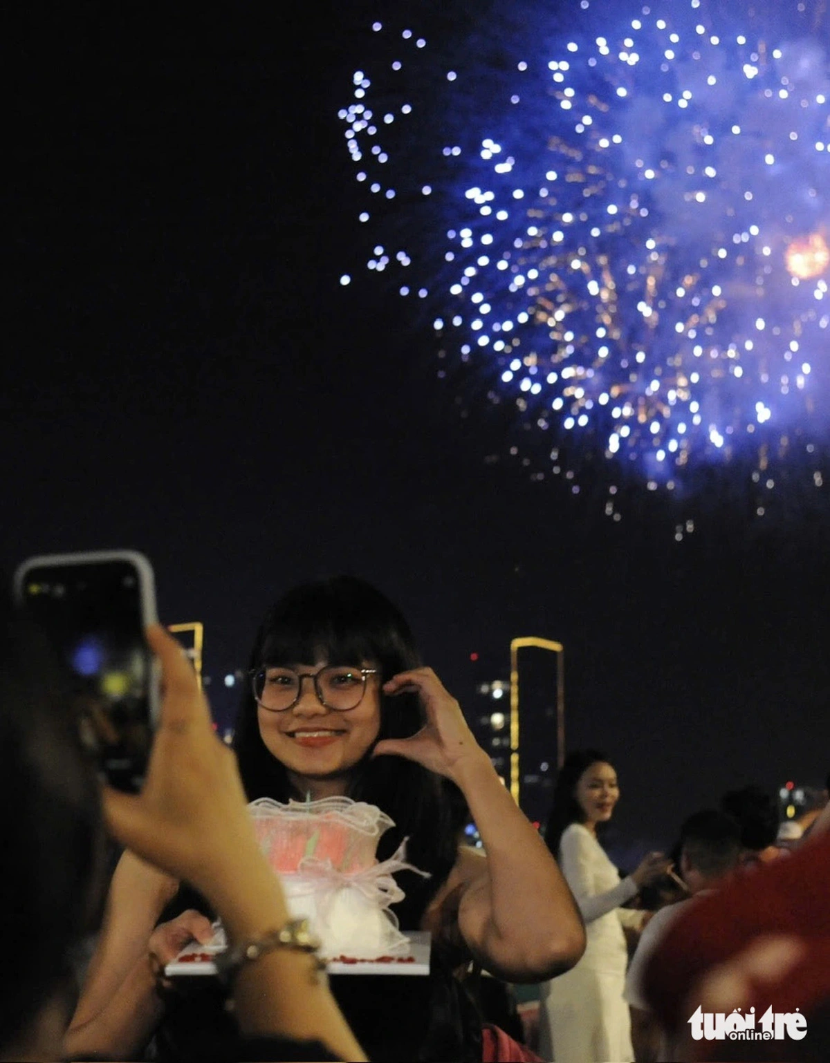 25-year-old Phuong Quynh, from Ho Chi Minh City’s Binh Thanh District, celebrates her birthday under a fireworks display. Photo: Khanh Giang