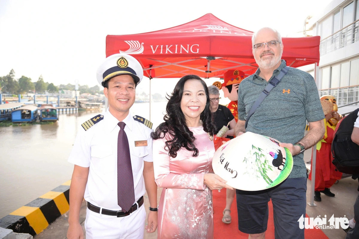 Luong Thi Diem Trang (C), director of My Tho Port Joint Stock Company in My Tho City, Tien Giang Province, presents a ‘non la’ (Vietnamese palm-leaf conical hat) to the head of the international tourist group (R) upon their arrival at My Tho Cruise Port on January 29, 2025. Photo: Hoai Thuong / Tuoi Tre