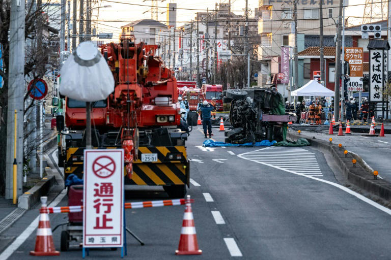 Part of a truck salvaged from a sinkhole sits on its side as rescue operations continue for the driver at a prefectural road intersection in Yashio, Saitama Prefecture. Photo: AFP