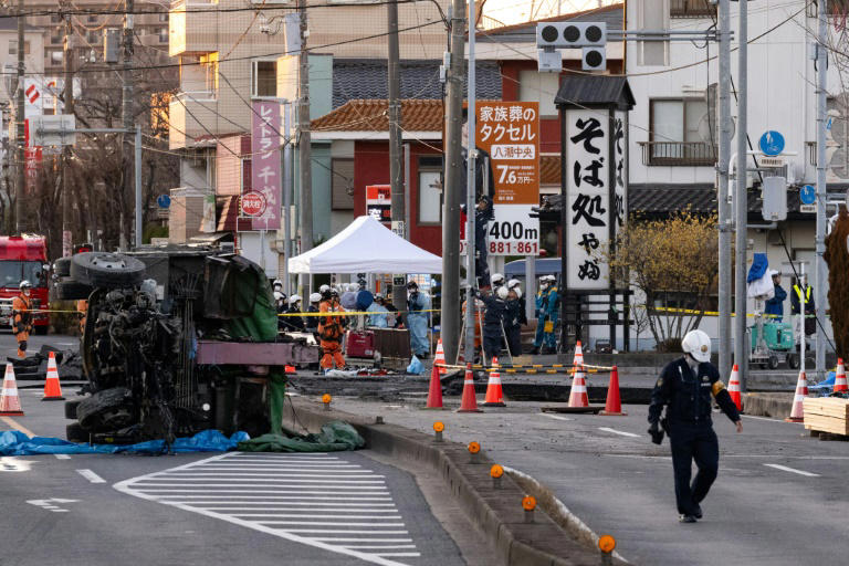 Part of a truck salvaged from a sinkhole sits on its side as rescue operations continue for the driver at a prefectural road intersection in Yashio, Saitama Prefecture. Photo: AFP