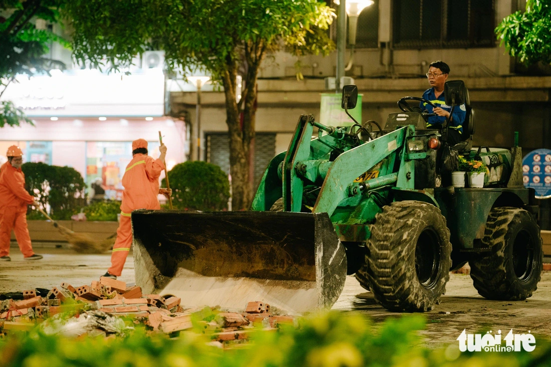 At around midnight, specialized bulldozers are deployed to speed up the cleaning of Nguyen Hue Flower Street. Photo: Thanh Hiep / Tuoi Tre