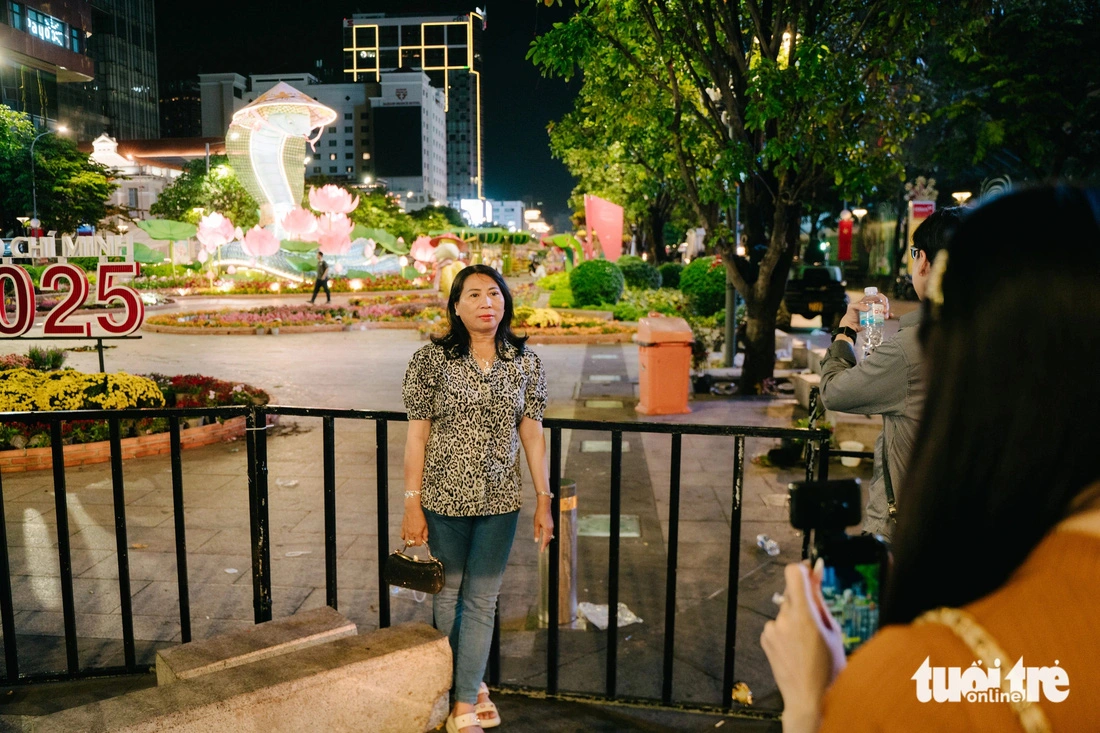 My Anh, residing in Tan Binh District, takes photos with Nguyen Hue Flower Street in Ho Chi Minh City on February 2, 2025. Photo: Thanh Hiep / Tuoi Tre