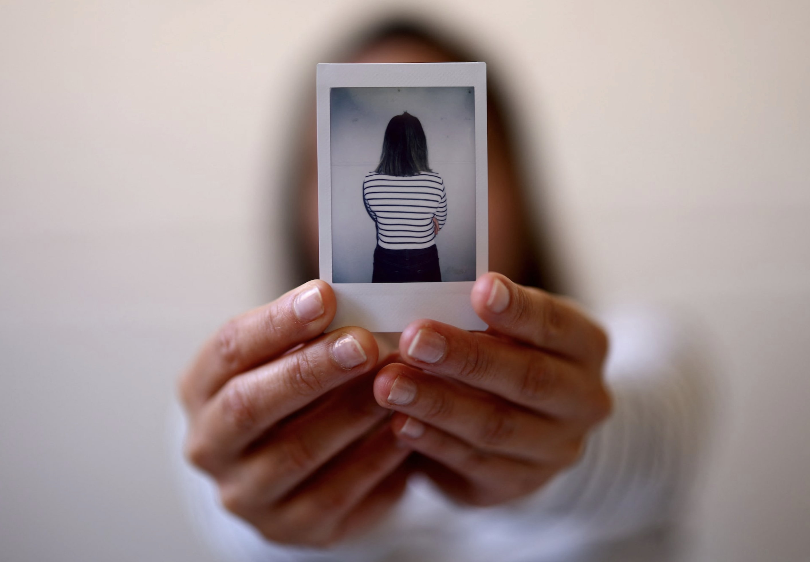 A suspected victim of modern slavery, who was initially denied state support after Britain introduced a tougher immigration policy, holds an Instax photograph of herself while posing for a portrait following an interview with Reuters in London, Britain, September 19, 2024. Photo: Reuters