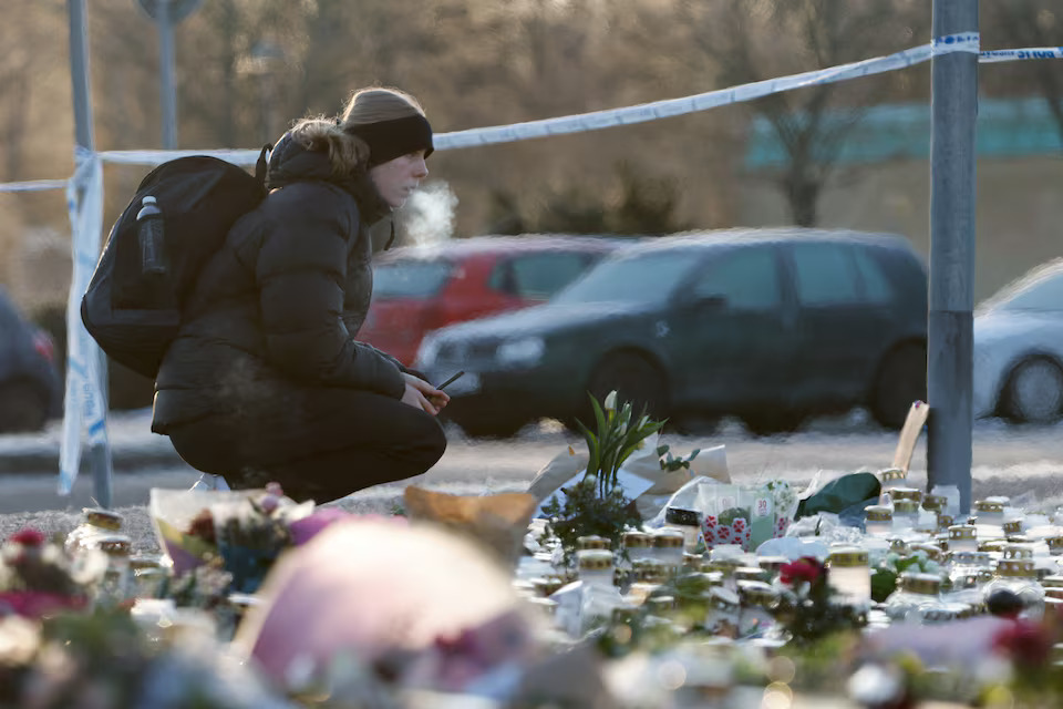 [2/4]A person looks on next to candles and flowers placed near the Risbergska school, following a deadly shooting attack at the adult education centre, in Orebro, Sweden, February 7, 2025. Photo: Reuters