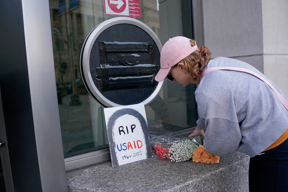 A person leaves flowers, next to a USAID sign which is covered over, at the agency's headquarters in Washington, U.S., February 7, 2025. Photo: Reuters