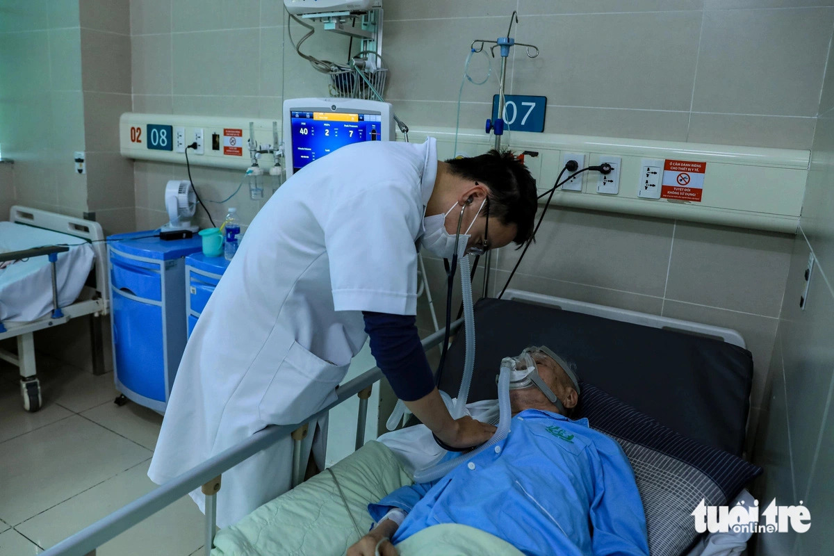 Dr. Bui Nhu Khoat from the Respiratory Center of Bach Mai Hospital in Hanoi, Vietnam, examines an elderly patient with a respiratory illness in the emergency room. Photo: D. Khang / Tuoi Tre