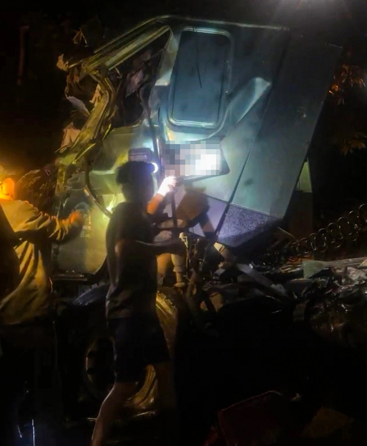 Local residents force open a trailer truck door to rescue the driver and his assistant after a crash with a sleeper bus in Son La Province, northern Vietnam, February 21, 2025. Photo: Supplied