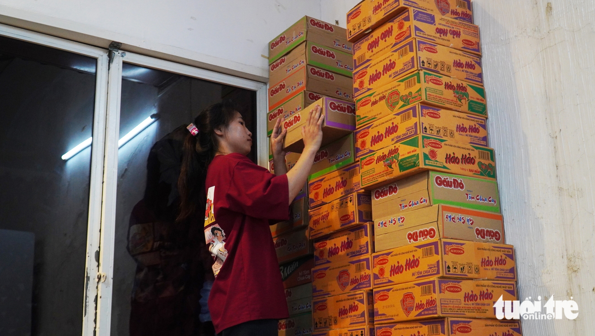 Ngo Huyen Tran, a staff member at the noodle shop, helps organize cartons of noodles from generous donors. Photo: Thanh Huyen / Tuoi Tre