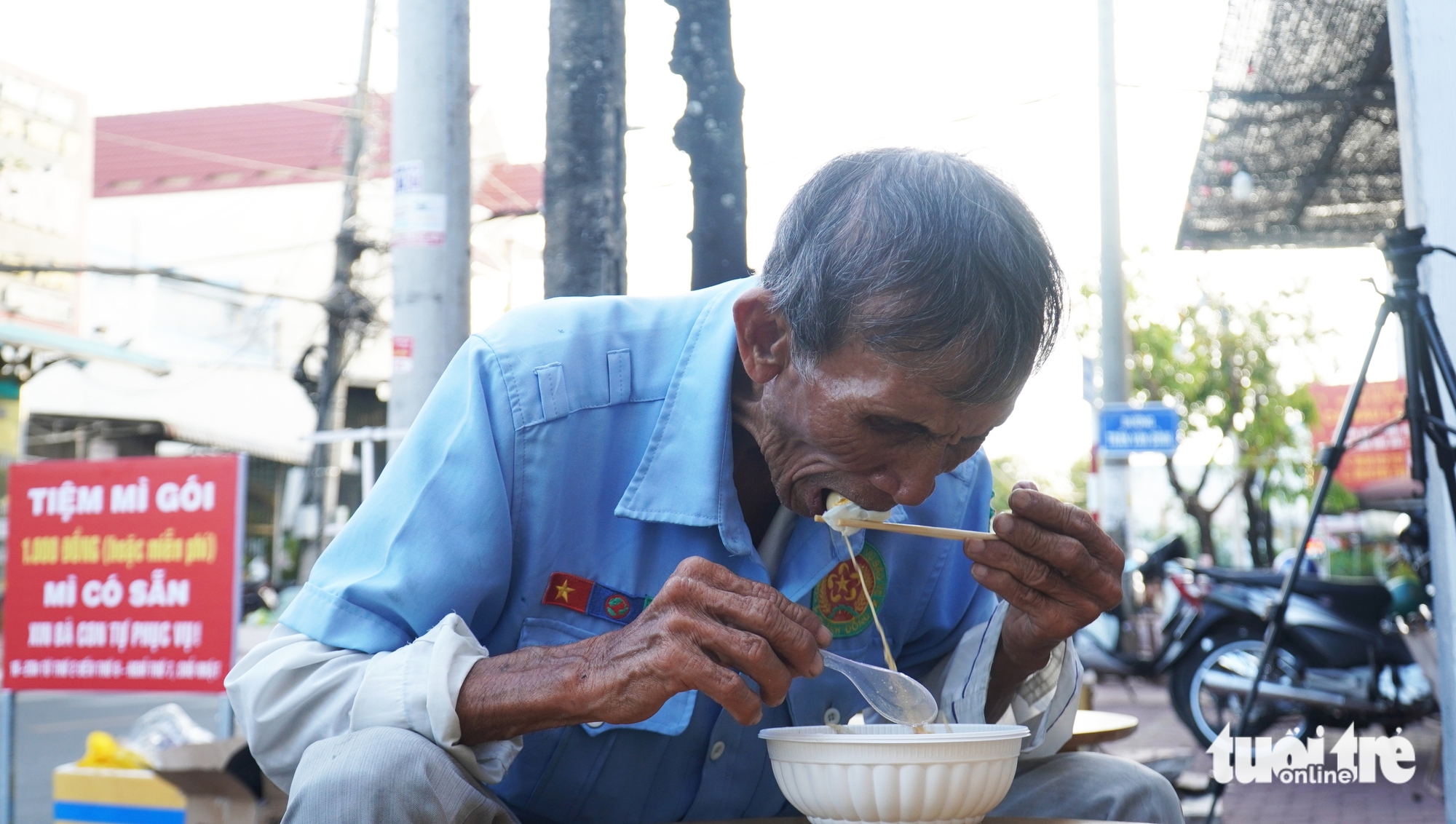 Chau Phu Vinh, a 82-year-old native of Tran Van Thoi District in Ca Mau Province, enjoys his bowl of VND1,000 noodles served with sausage, egg, and vegetables. Photo: Thanh Huyen / Tuoi Tre