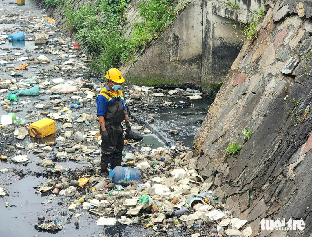 A sanitation employee collects garbage in a section of Canal 19/5 in Tan Phu District, Ho Chi Minh City. Photo: Ngoc Khai / Tuoi Tre