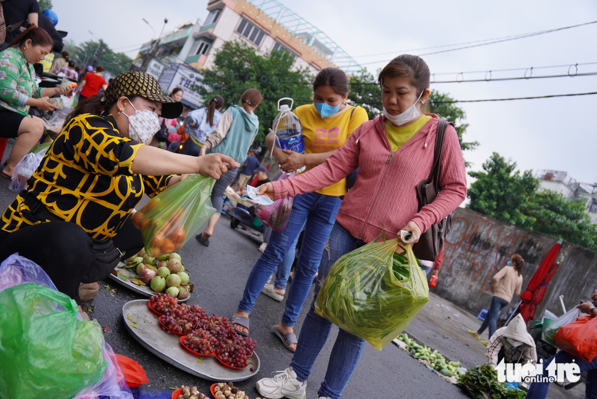 Diem (R), a 38-year-old worker from Binh Tan District, buys vegetables on small plates at Tan Tao makeshift market in Tan Tao Ward, Tan Binh District, Ho Chi Minh City. Photo: An Vi / Tuoi Tre