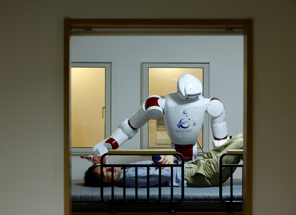 AIREC, an artificial intelligence (AI)-driven humanoid robot, demonstrates a manoeuvre for changing diapers or preventing bedsores with a researcher at Waseda University's laboratory in Tokyo, Japan February 17, 2025. Photo: Reuters