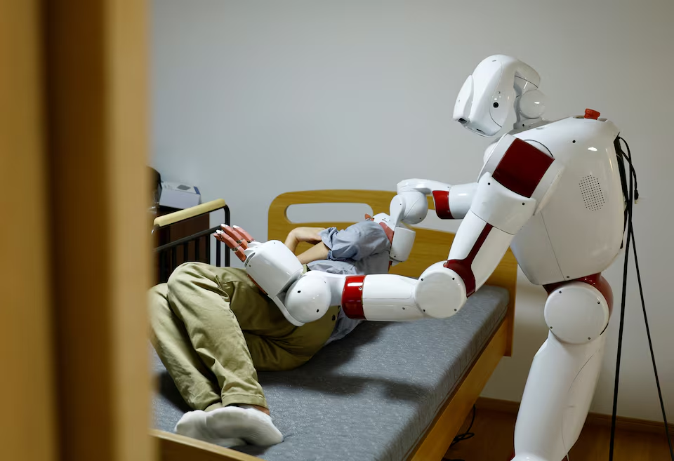 AIREC, an artificial intelligence (AI)-driven humanoid robot, demonstrates a manoeuvre for changing diapers or preventing bedsores with a researcher at Waseda University's laboratory in Tokyo, Japan February 17, 2025. Photo: Reuters