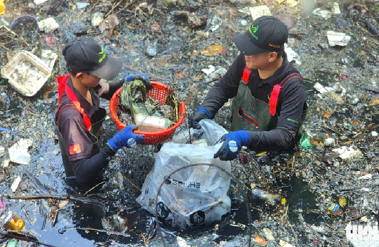 Volunteers put trash into bags to bring it ashore. Photo: Ngoc Khai / Tuoi Tre