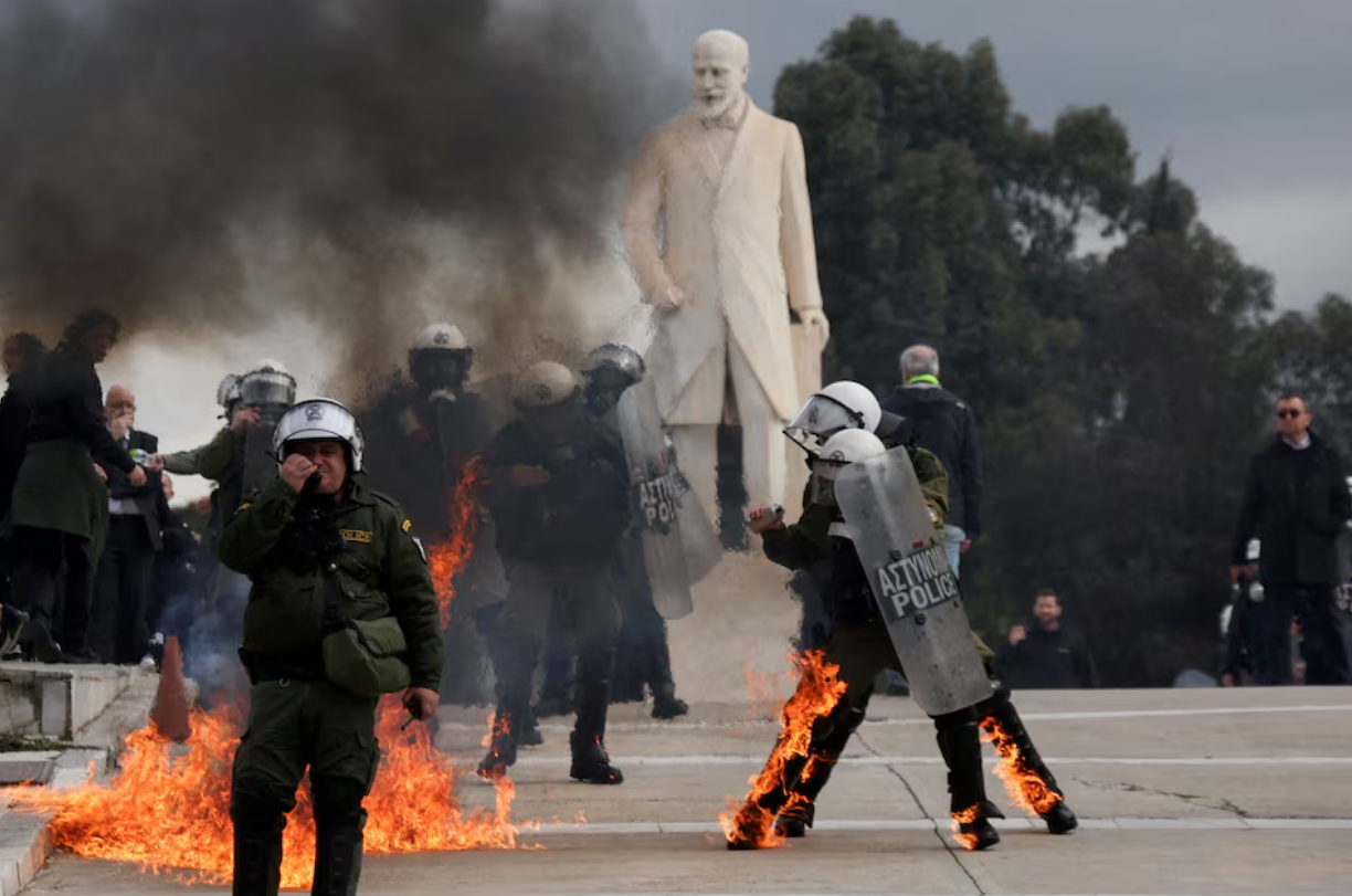 Riot police walk with their gear on fire, after being struck by Molotov cocktails, at a protest near the Greek parliament, in Athens, February 28. Photo: Reuters