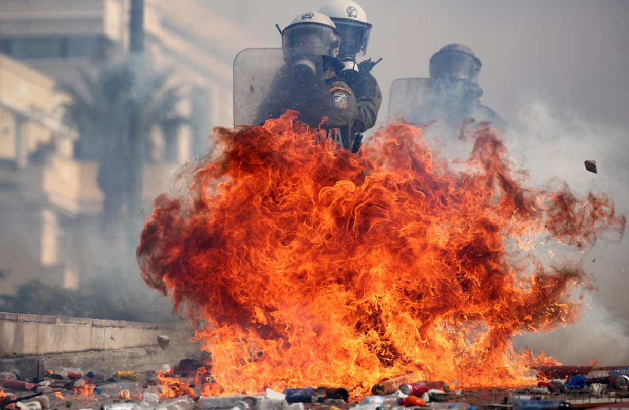 Riot police react to ignited Molotov cocktails thrown by demonstrators, at a protest near the Greek parliament, in Athens, Greece, February 28. Photo: Reuters