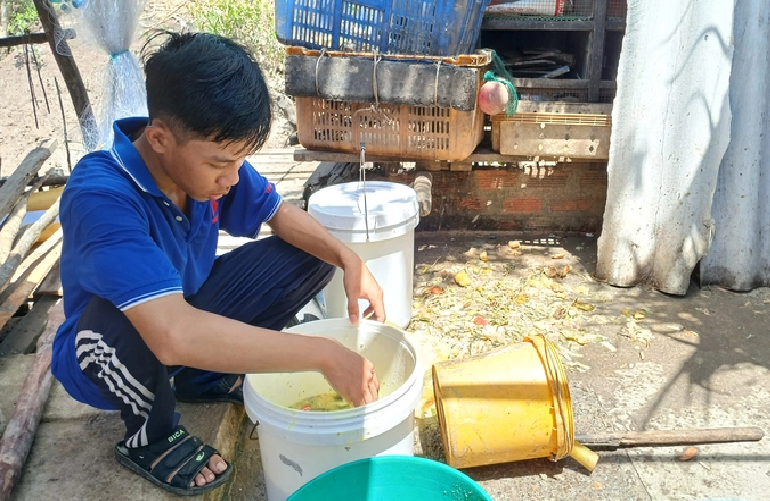 Do prepares leftover food for his family’s pigs and chickens. Photo: Thanh Huyen / Tuoi Tre