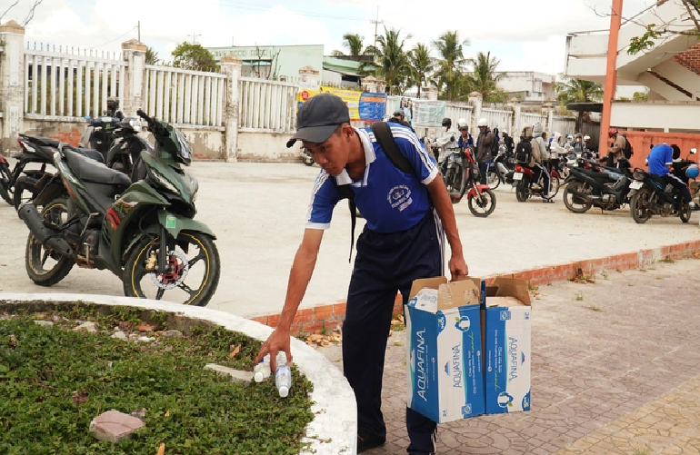 Do picks up discarded water bottles in the schoolyard. Photo: Thanh Huyen / Tuoi Tre