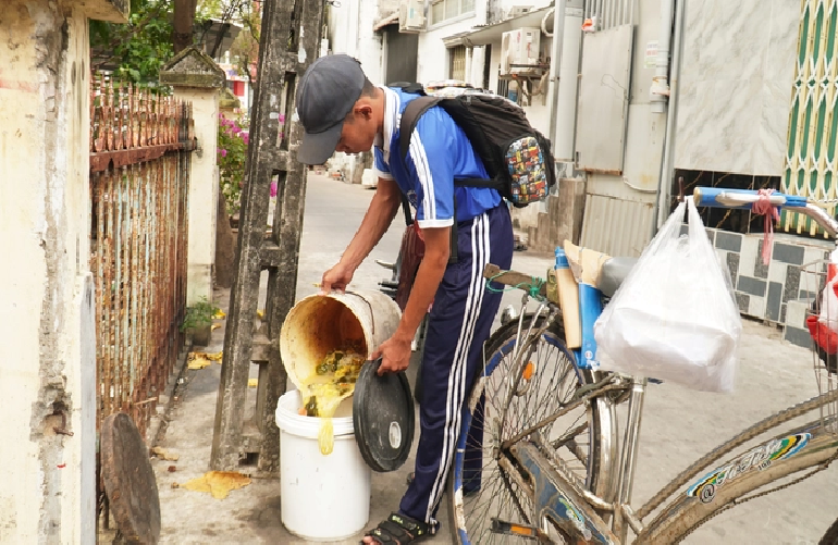 Do collects leftover food on the way home from school to feed his family’s pigs. Photo: Thanh Huyen / Tuoi Tre